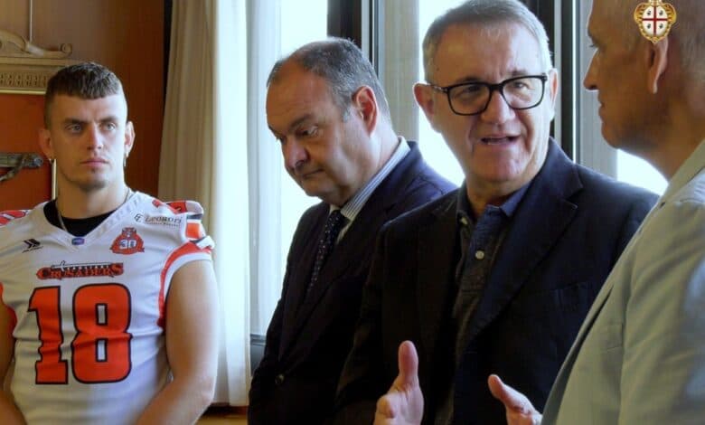 Il presidente del Consiglio regionale Piero Comandini parla durante la cerimonia, accanto a un giocatore dei Crusaders in divisa da gioco