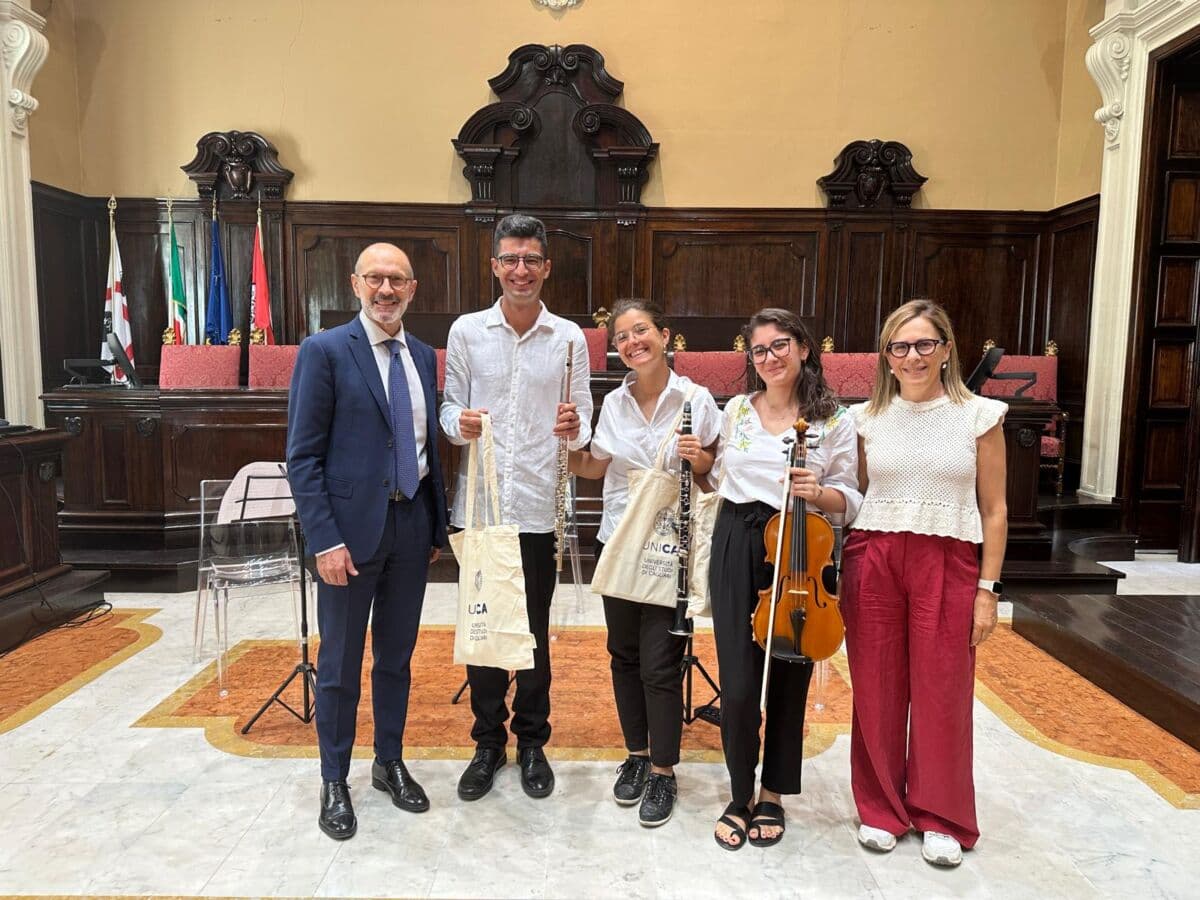 I tre musicisti con i loro strumenti posano nell’aula magna del rettorato insieme al prorettore vicario Gianni Fenu e alla capo di gabinetto Alessandra Orrù