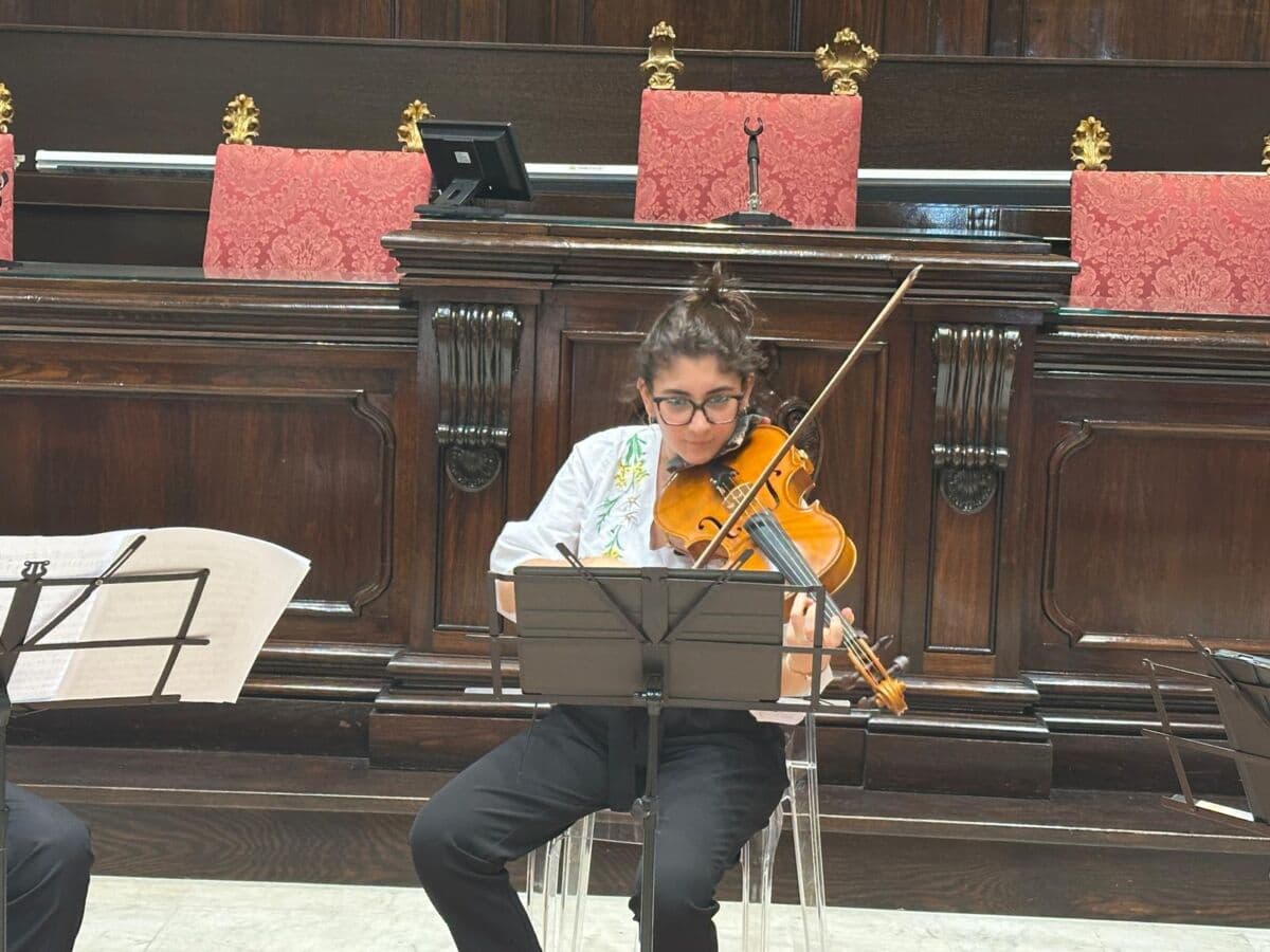 Teresa Lavena suona la viola seduta davanti al leggio, nell’aula magna del rettorato